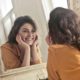 Woman looking at herself in the mirror looking content