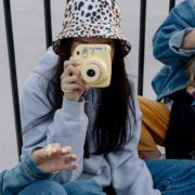 Picture of girl holding a polaroid camera amongst her friends