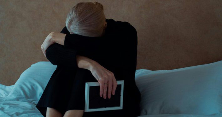 Woman sad clutching a photo frame