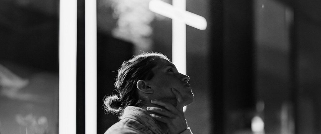 Woman looking up with cross behind