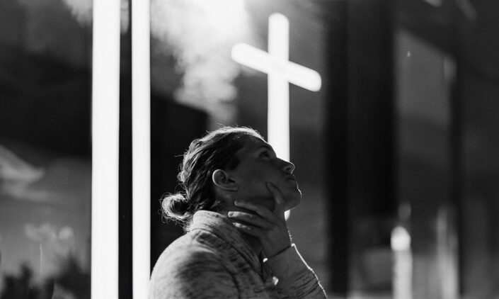 Woman looking up with cross behind