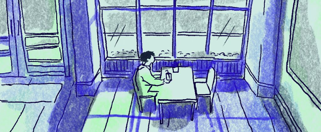 A man is sitting alone in a cafe